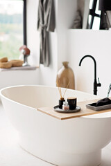 Empty white bathtub in modern apartment with stylish loft style interior design, home decor. Spa concept, relaxation. Soft selective focus.