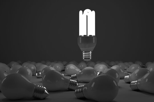 Digital composite image of lit energy efficient lightbulb over bulbs