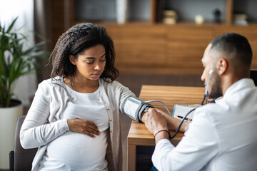 African american man gynecologist checking pregnant woman heart rate