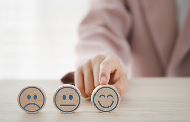 closeup businesswoman finger pointing on happy emotion face on wooden piece arranged on table for satisfaction survey