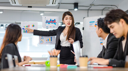 Asian young beautiful professional successful businesswoman presenter standing smiling in front of glass board after presenting while male female colleagues clapping hands thank you in meeting room