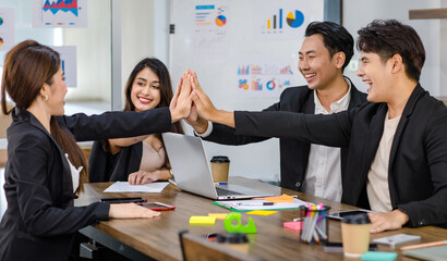 Group of millennial Asian young professional successful male businessman and female businesswoman sitting smiling holding hands high five showing unity together in office meeting room after workshop