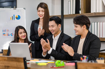 Group of millennial Asian young professional successful male businessmen and female businesswomen in formal suit sitting standing smiling screaming shouting holding fists up celebrating together