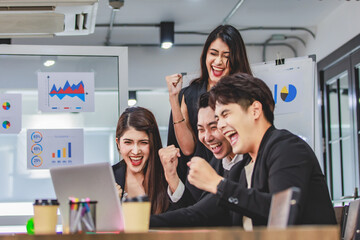 Group of millennial Asian young professional successful male businessmen and female businesswomen in formal suit sitting standing smiling screaming shouting holding fists up celebrating together