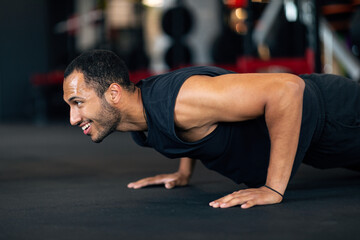 Fototapeta na wymiar Muscular Young African American Man Doing Floor Push Up Exercise In Gym