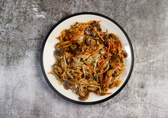 Vegetarian Lo Mein Noodles on a round plate on a dark background. Top view, flat lay
