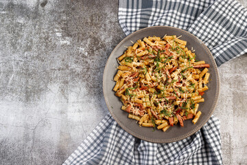 Homemade macaroni pasta with ham and cheese on a round plate on a dark background. Top view, flat lay