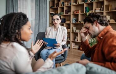 Calm european millennial female psychologist consults quarreling multiracial husband and wife