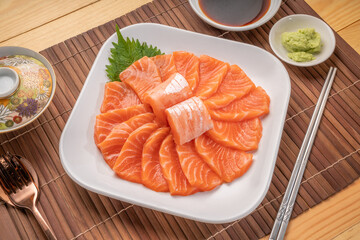 Sliced ​​Fresh Salmon white plate on wooden background, Salmon sashimi salmon sashimi with sauce and wasabi reday to eat.
