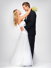 Happy couple hug after wedding against a studio mockup background with a smile and bouquet. Romantic young man and woman dancing with fashion, elegant and fancy suit and dress after marriage event