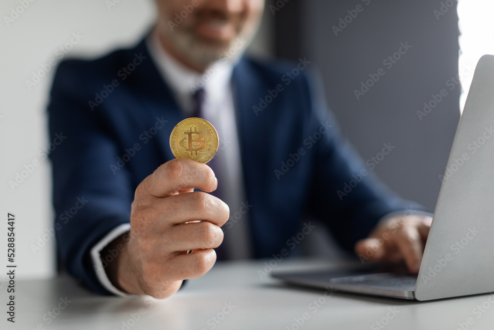 Poster cryptocurrency trading. unrecognizable smiling businessman sitting at desk and showing golden bitcoi