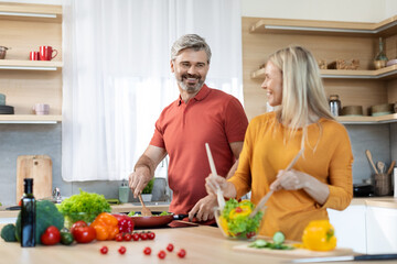 Loving spouses preparing healthy meal together, kitchen interior