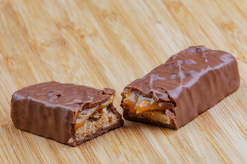 Delicious chocolate and caramel bar isolated on a wooden background