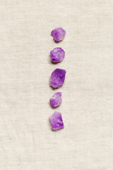 Flat lay from purple amethyst crystals on textile background with copy space,  top view natural beautiful gemstone. Amethyst stone healing crystal, rocks quartz mineral close up