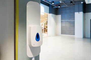 Automatic hand sanitizer dispenser at the entrance of the supermarket. Covid-19 spread prevention.