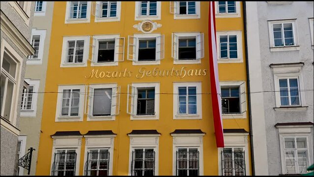 Salzburg, Austria, August 2022. Tilt footage of Mozart's house in the old town. The bright yellow facade features the inscription Mozart's house.