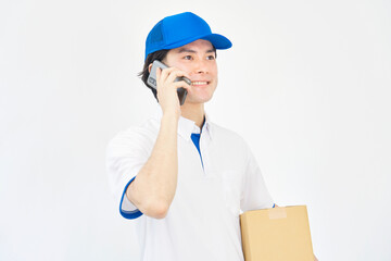 白背景でスマホで電話する宅配業者の男性