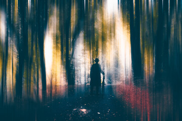 A mysterious figure wearing a long coat and fedora hat walking in the forest - obrazy, fototapety, plakaty