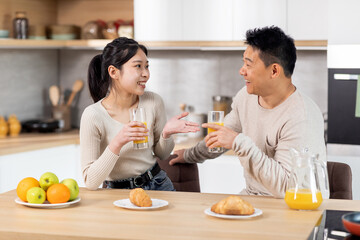 Obraz na płótnie Canvas Happy asian spouses having fun while eating at kitchen