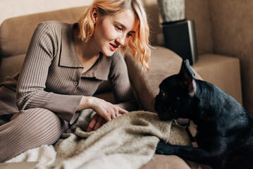 Happy woman play with their dog black french bulldog. Girl petting a puppy indoors in the stylish...