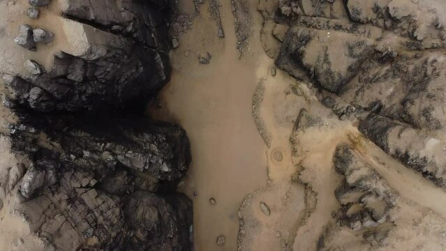 Drone topdown video of a gorge, gully or canyon. Drone flies slowly forward while facing down into the chasm or rocky abyss. Located in Lima, Peru in Chorrillos district. Near beach called "La Chira".