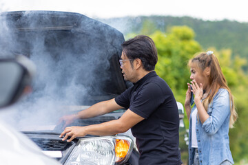 Car engine overheating, smoke out from engine front hood man help to check with shocked woman driver