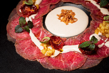 Meat carpaccio on the black plate