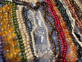 Сlose up of colorful beads. Beads made natural gems turquoise, malachite, mother of pearl, jade, quartz, agate, lapis lazuli, jasper, cacholong, tiger's eye stone, topaz, fluorite.