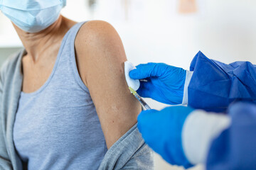 Doctor holding syringe making covid 19 vaccination injection dose in shoulder of female patient...