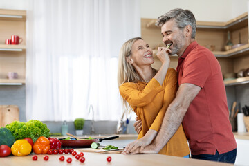 Happy middle aged spouses preparing delicious dinner together