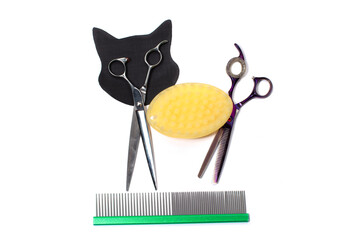 Fototapeta premium Set of different combs and brushes for grooming pets on a white background with shadow reflection. A creative cat figurine made from grooming tools.