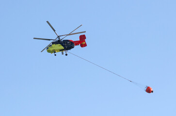 Fototapeta na wymiar Helicopter with water to extinguish a fire