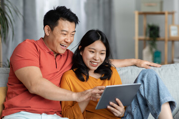 Obraz premium Happy asian lovers using digital tablet, home interior