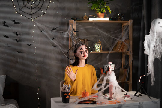 Young asian girl and professional beauty make up artist vlogger recording Halloween makeup tutorial in home studio to share on website or social media. Blogger use smartphone on tripod