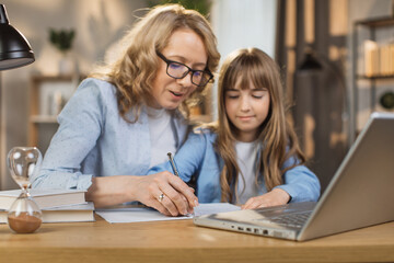Little kid writing and sketching in notebook, with mother's encouragement and assistance. Mom and daughter, teaching and interests go hand in hand. Children's abilities inventiveness developing.