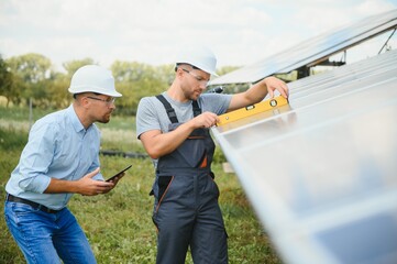 Male engineer in protective helmet installing solar photovoltaic panel system. Alternative energy ecological concept.