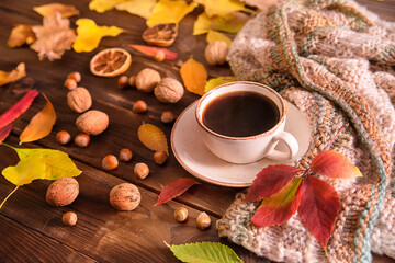 Autumn, autumn leaves, a cup of hot coffee and a warm scarf on a wooden table background. Seasonal, morning coffee, sunday rest and still life concept.

