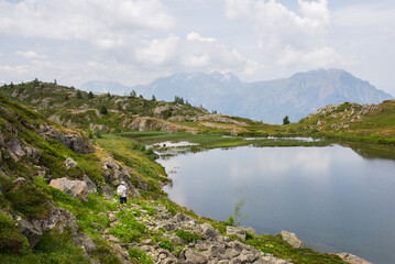 Fototapeta na wymiar un lac de montagne dans les Alpes. Un homme se promène dans les bois.