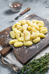 Raw homemade potato gnocchi with fork on wooden cutting board. Gray background. Top view