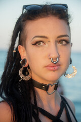 portrait of sensitive young teenager woman, girl with dark hair, dreadlocks, many piercings