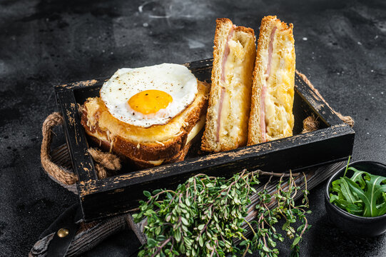 French toasts croque monsieur and croque madame with sliced ham, melted emmental cheese and egg. Black background. Top view