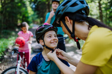 Young family with little children preapring for bike ride, standing with bicycles in nature.