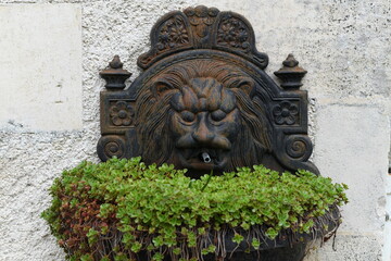 Iron Lion head statue used as a fountain on a wall.