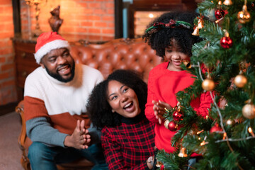 Family, father, mother and children are rejoicing in decorating the Christmas tree in the house.