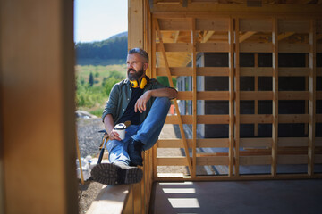 Handyman resting and having break when working on wooden construction site, diy eco-friendly homes...