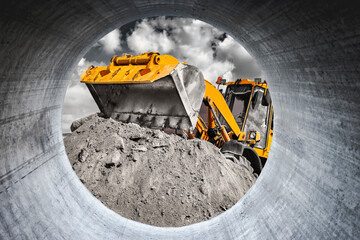 A large front loader pours sand into a pile at a construction site. Transportation of bulk...