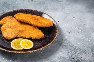 Roasted breaded german weiner schnitzel on a plate. Gray background. Top view. Copy space - obrazy, fototapety, plakaty