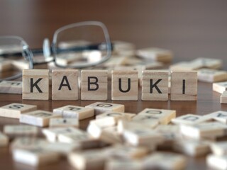 kabuki word or concept represented by wooden letter tiles on a wooden table with glasses and a book