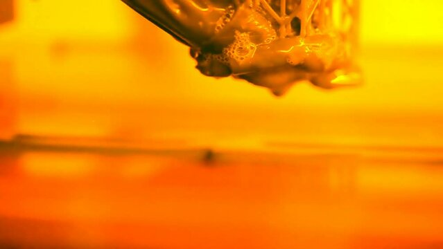 Stereolithography DPL SLA 3d printer create and liquid drips, platform slowly move with liquid close-up. Progressive modern additive technology 3D printing, create scaled model by UV polymerization