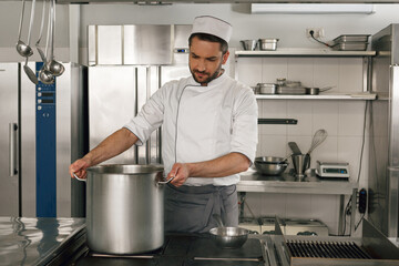 Chef cooking tasty dish in kitchen of restaurant using modern equipment